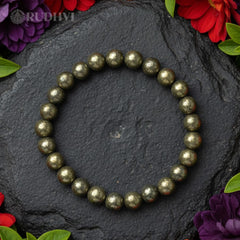 Pyrite beaded bracelet on a dark stone surface with flowers around