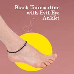 Anklet with black tourmaline and evil eye charm on a foot against a pink background